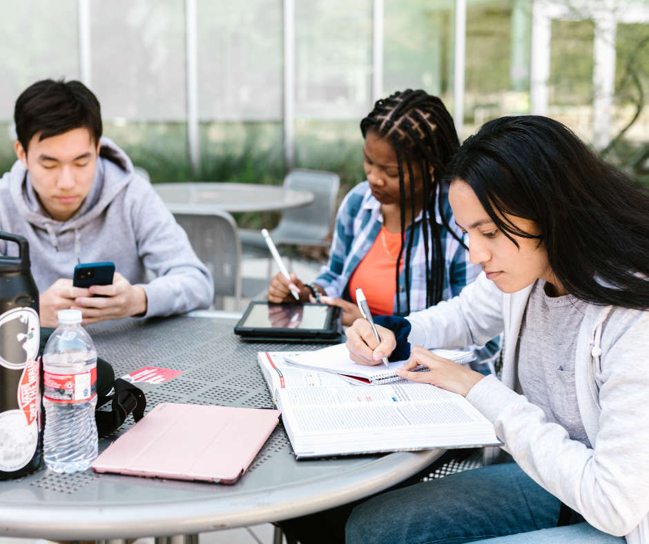 three students working at an outdoor table