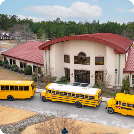 Yellow school buses parked on a curved driveway in front of a new, clean school building.