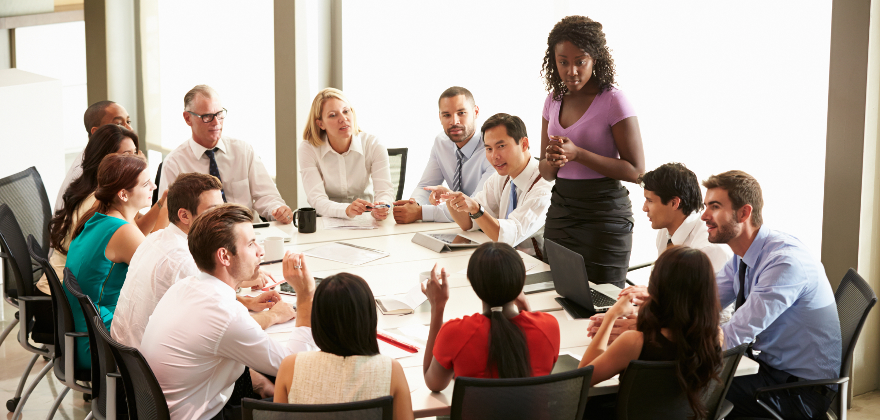 African American woman running a meeting around a boardroom