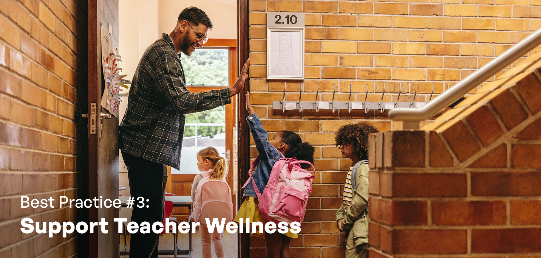 A teacher at the classroom door high fiving students as they enter the classroom