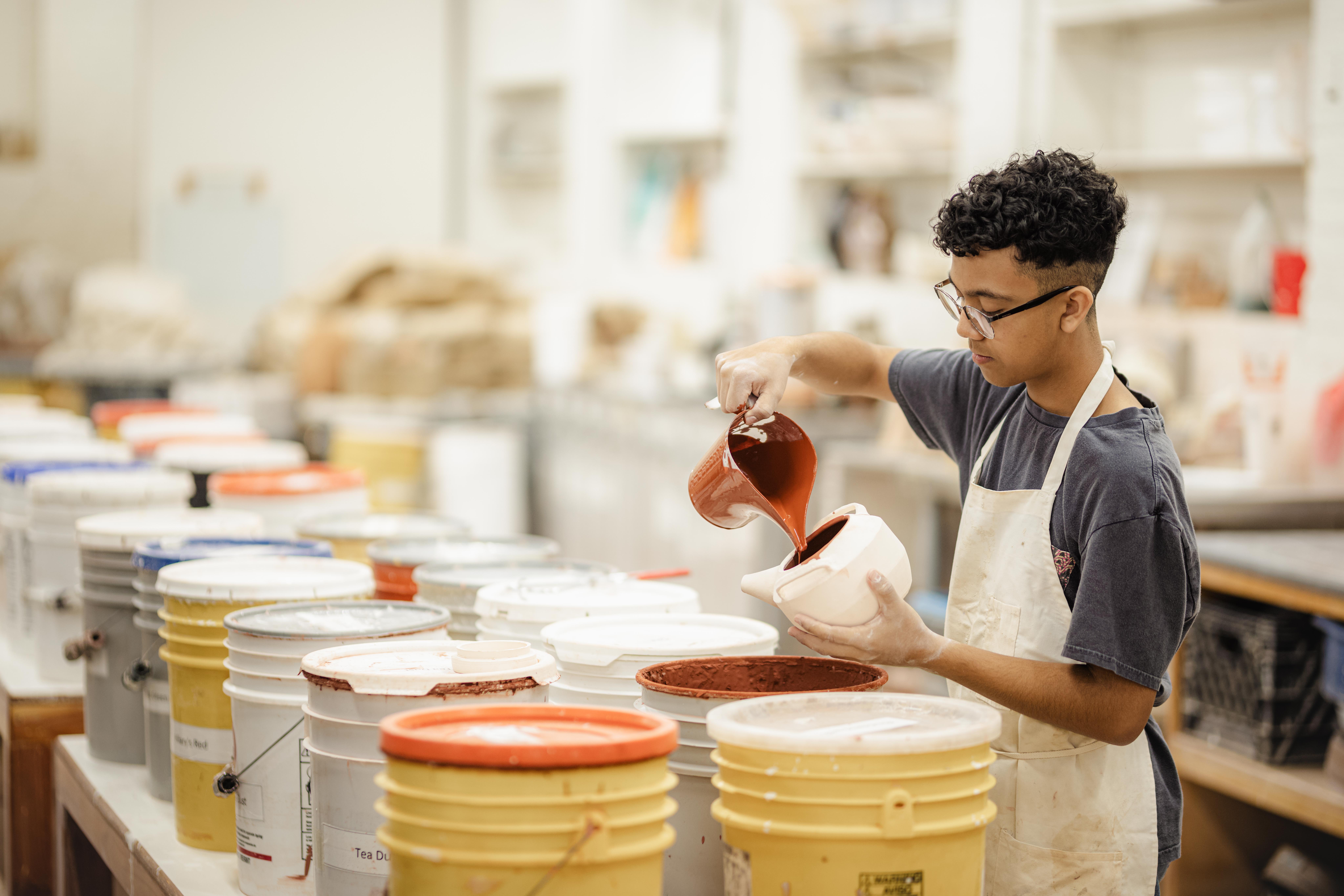 student glazing pottery