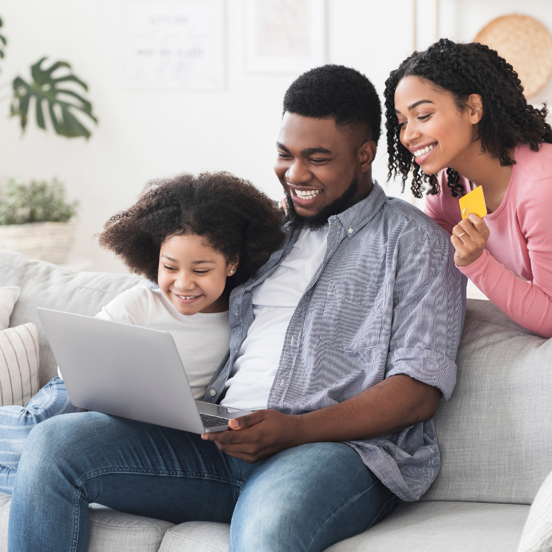 A family of three looks at a laptop computer together