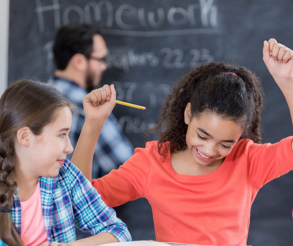 two students in a classroom smile while working