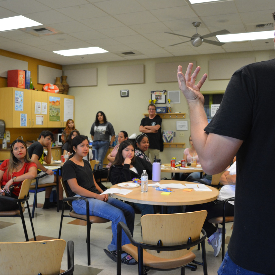 A class full of students and parents listens to a speaker